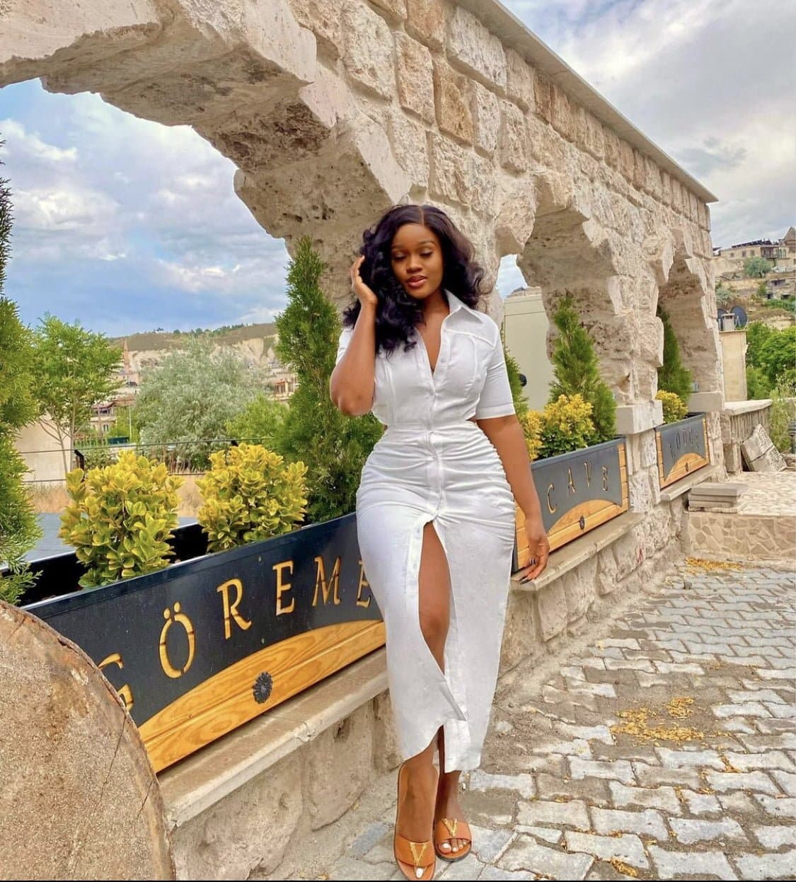 Ceec in a white dress with a slit. 